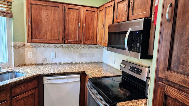 1718 Gentle Wind Dr, Arlington, TX 76018 - kitchen with appliances with stainless steel finishes, tasteful backsplash, light stone counters, and brown cabinetry