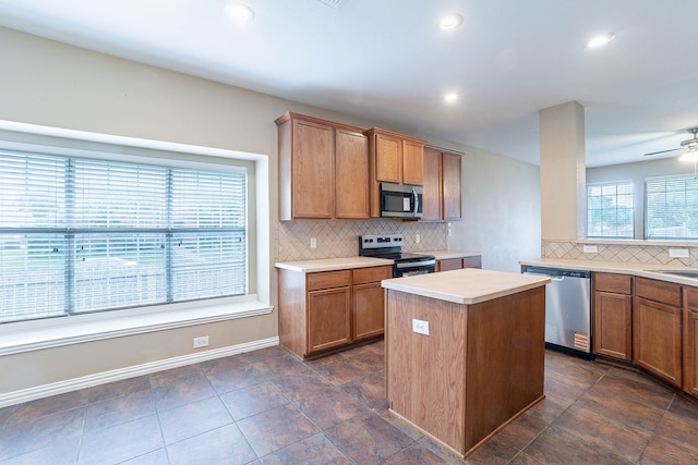 7001 Bickers Dr, Rowlett, TX 75089 - kitchen featuring appliances with stainless steel finishes, tasteful backsplash, light countertops, a kitchen island, and brown cabinetry