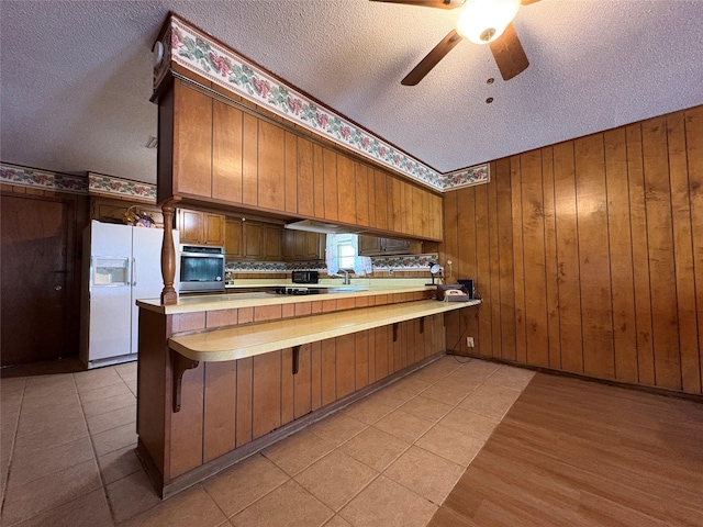 1605 NE 17th, Paris, TX 75460 - kitchen featuring white fridge with ice dispenser, a textured ceiling, oven, brown cabinetry, and a peninsula