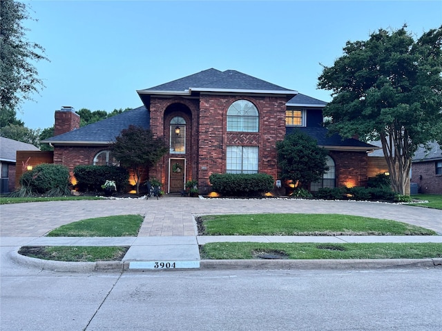 3904 Davis Cir, Plano, TX 75023 - traditional home with brick siding, a chimney, a shingled roof, and curved driveway
