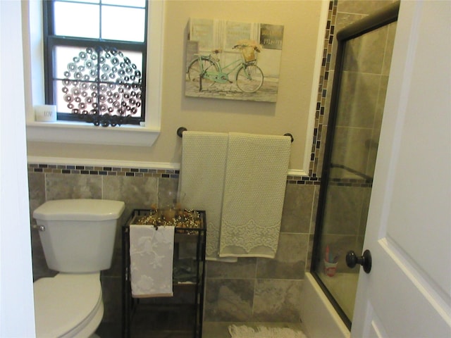 3307 Shawnee Trl, Lake Worth, TX 76135 - bathroom featuring tile walls, toilet, healthy amount of natural light, enclosed tub / shower combo, and wainscoting