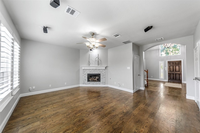 1557 Crystal Pass, Allen, TX 75002 - unfurnished living room featuring arched walkways, a ceiling fan, dark wood-style flooring, and a fireplace