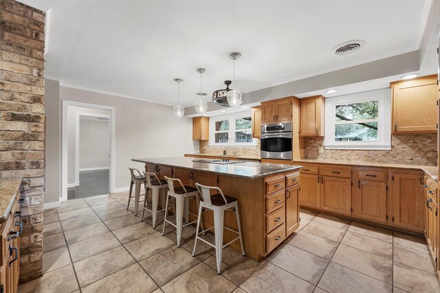 2225 Wooded Acres Dr, Waco, TX 76710 - kitchen featuring oven, backsplash, a center island, a kitchen breakfast bar, and crown molding