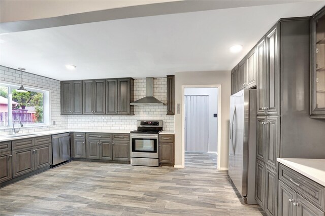 1510 Bowie St, Garland, TX 75042 - kitchen featuring stainless steel appliances, wall chimney range hood, light wood-style floors, tasteful backsplash, and recessed lighting