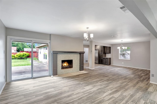 1510 Bowie St, Garland, TX 75042 - unfurnished living room with a chandelier, healthy amount of natural light, light wood-style floors, and a fireplace with flush hearth