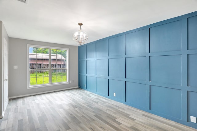 1510 Bowie St, Garland, TX 75042 - unfurnished room featuring a chandelier, light wood-type flooring, and a decorative wall