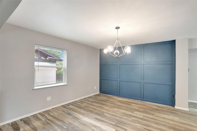 1510 Bowie St, Garland, TX 75042 - empty room featuring a decorative wall, light wood-style floors, and a chandelier