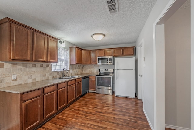 708 Simpson Ter, Bedford, TX 76021 - kitchen with appliances with stainless steel finishes, a sink, dark wood finished floors, backsplash, and a textured ceiling