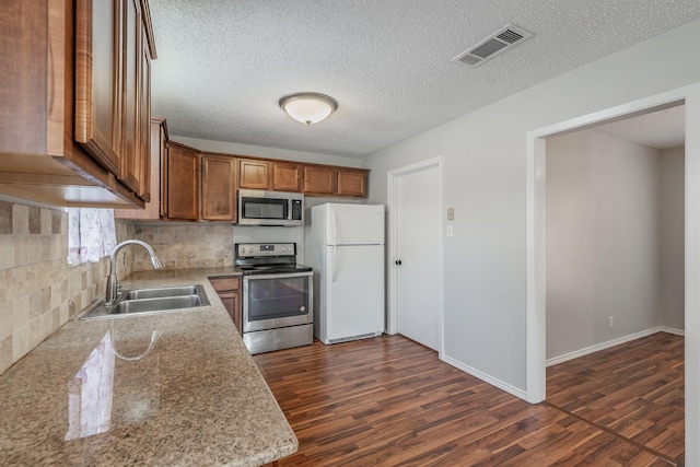 708 Simpson Ter, Bedford, TX 76021 - kitchen with appliances with stainless steel finishes, a sink, tasteful backsplash, a textured ceiling, and dark wood-style flooring