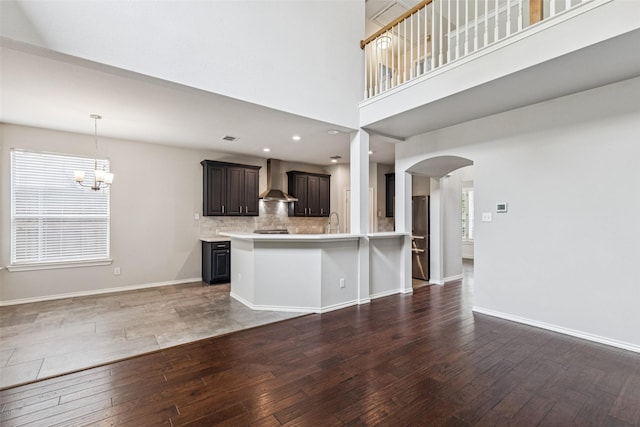 2210 Garden Crest Dr, Rockwall, TX 75087 - kitchen with wall chimney range hood, hardwood / wood-style flooring, arched walkways, light countertops, and a chandelier
