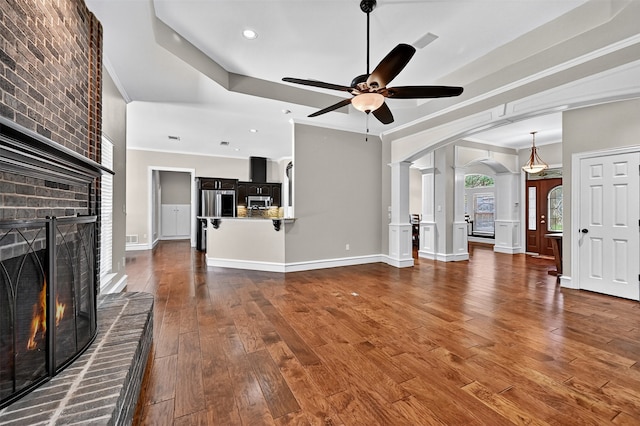 688 Lazy Acres Cir, Pottsboro, TX 75076 - unfurnished living room featuring arched walkways, a fireplace, a ceiling fan, crown molding, and ornate columns