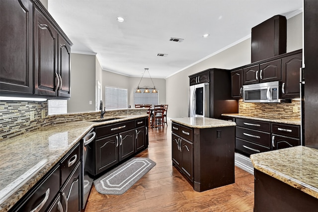 688 Lazy Acres Cir, Pottsboro, TX 75076 - kitchen featuring stainless steel appliances, a sink, wood finished floors, ornamental molding, and backsplash