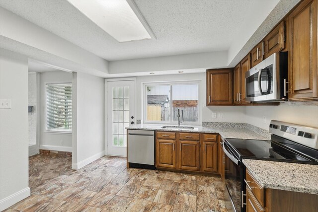 3217 Redwood St, Bedford, TX 76021 - kitchen with appliances with stainless steel finishes, light stone counters, stone finish floors, and baseboards