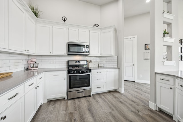 3205 Tradition Ct, Rowlett, TX 75088 - kitchen featuring appliances with stainless steel finishes, white cabinets, light wood-type flooring, and tasteful backsplash