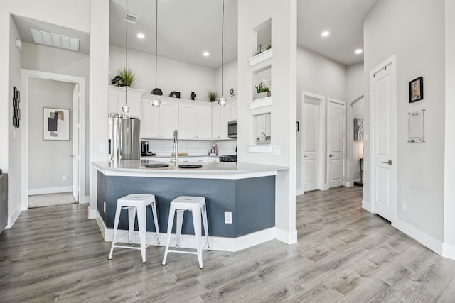3205 Tradition Ct, Rowlett, TX 75088 - kitchen featuring stainless steel appliances, a breakfast bar area, decorative backsplash, white cabinetry, and a high ceiling