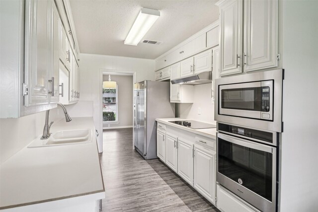 2201 Briarwood Blvd, Arlington, TX 76013 - kitchen with stainless steel appliances, white cabinetry, light countertops, dark wood finished floors, and under cabinet range hood