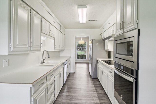 2201 Briarwood Blvd, Arlington, TX 76013 - kitchen featuring stainless steel appliances, light countertops, white cabinets, dark wood-style floors, and a textured ceiling