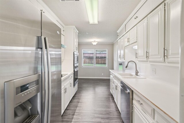 2201 Briarwood Blvd, Arlington, TX 76013 - kitchen featuring stainless steel appliances, a textured ceiling, light countertops, dark wood finished floors, and white cabinets