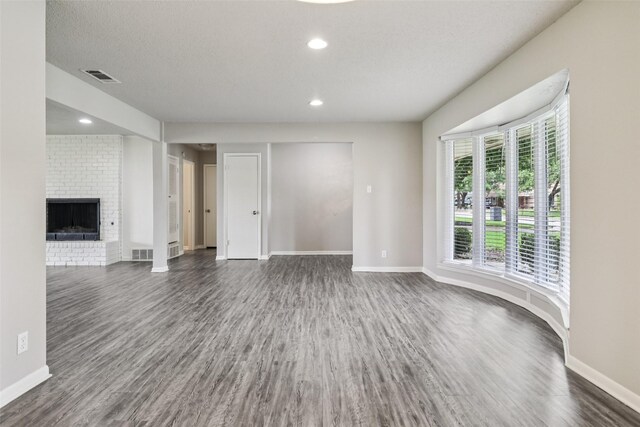 2201 Briarwood Blvd, Arlington, TX 76013 - unfurnished living room featuring dark wood-style flooring, a brick fireplace, and recessed lighting
