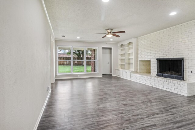 2201 Briarwood Blvd, Arlington, TX 76013 - unfurnished living room with a textured ceiling, ceiling fan, dark wood finished floors, a brick fireplace, and built in features