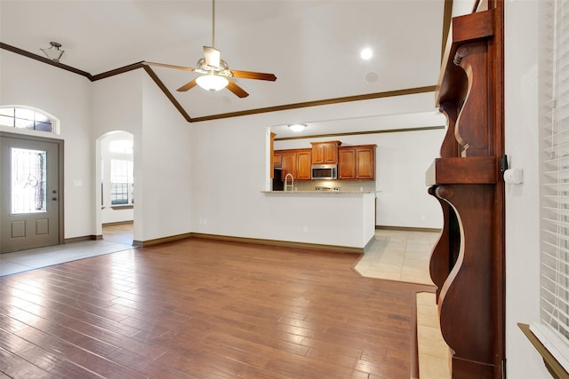 2111 Renaissance Dr, Denison, TX 75020 - unfurnished living room with ornamental molding, ceiling fan, arched walkways, light wood-type flooring, and a sink