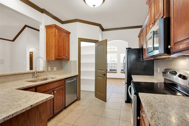 2111 Renaissance Dr, Denison, TX 75020 - kitchen with appliances with stainless steel finishes, arched walkways, a sink, crown molding, and tasteful backsplash