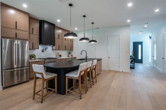 4322 Sexton Ln, Dallas, TX 75229 - kitchen featuring premium appliances, exhaust hood, a sink, light wood finished floors, and dark countertops