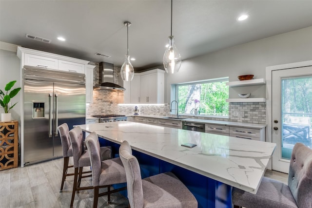 711 Majestic Oaks Dr, Oak Point, TX 75068 - kitchen with stainless steel appliances, wall chimney exhaust hood, white cabinetry, tasteful backsplash, and recessed lighting