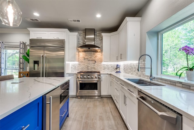 711 Majestic Oaks Dr, Oak Point, TX 75068 - kitchen with high quality appliances, wall chimney range hood, blue cabinetry, white cabinetry, and recessed lighting