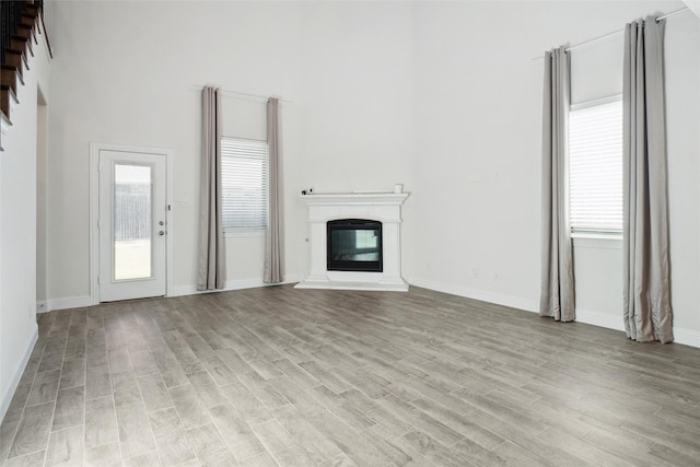 2929 Log Cabin Dr, Celina, TX 75009 - unfurnished living room featuring light wood finished floors, a glass covered fireplace, plenty of natural light, and a high ceiling