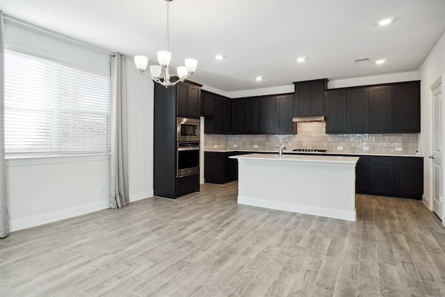 2929 Log Cabin Dr, Celina, TX 75009 - kitchen with stainless steel appliances, light countertops, backsplash, a chandelier, and light wood finished floors