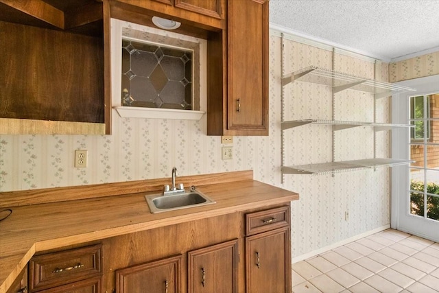 1506 Ridgeview Dr, Arlington, TX 76012 - kitchen with a sink, wallpapered walls, a textured ceiling, brown cabinetry, and light tile patterned floors