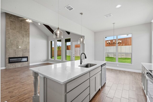 207 Mitchell Dr, Glen Rose, TX 76043 - kitchen with stainless steel dishwasher, wood finish floors, lofted ceiling, a fireplace, and a kitchen island with sink