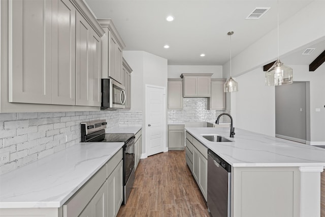 207 Mitchell Dr, Glen Rose, TX 76043 - kitchen with appliances with stainless steel finishes, gray cabinetry, recessed lighting, decorative backsplash, and a center island with sink