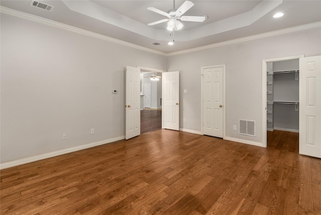 3616 Canyon Oaks Dr, Carrollton, TX 75007 - unfurnished bedroom with a tray ceiling, wood finished floors, crown molding, a walk in closet, and a ceiling fan