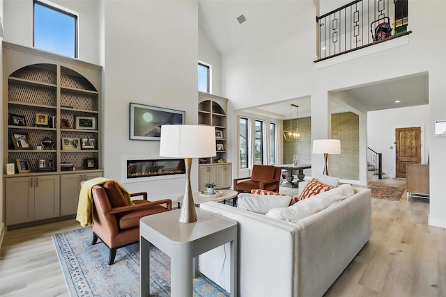 5901 Westworth Falls Way, Westworth Village, TX 76114 - living room featuring a high ceiling, light wood-style floors, stairway, healthy amount of natural light, and a glass covered fireplace