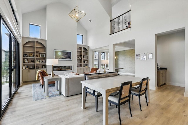 5901 Westworth Falls Way, Westworth Village, TX 76114 - dining area with built in features, high vaulted ceiling, light wood finished floors, plenty of natural light, and a glass covered fireplace
