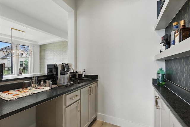 5901 Westworth Falls Way, Westworth Village, TX 76114 - bar featuring a sink, a chandelier, baseboards, a tray ceiling, and light wood-style flooring