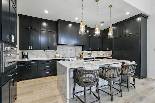 5901 Westworth Falls Way, Westworth Village, TX 76114 - kitchen with a sink, oven, light wood-type flooring, light stone counters, and tasteful backsplash