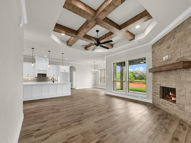 971 County Road 1304, Bridgeport, TX 76426 - unfurnished living room featuring a fireplace, coffered ceiling, light wood-style flooring, beam ceiling, and a sink