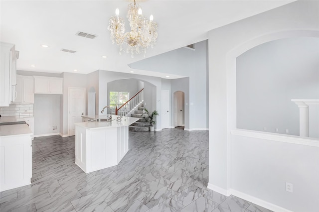 5718 Gloucester Dr, Tyler, TX 75707 - kitchen with a sink, arched walkways, light countertops, white cabinetry, and tasteful backsplash