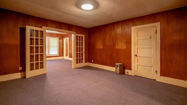 224 Pecan St, Dublin, TX 76446 - unfurnished room with french doors, wood walls, a textured ceiling, and carpet floors