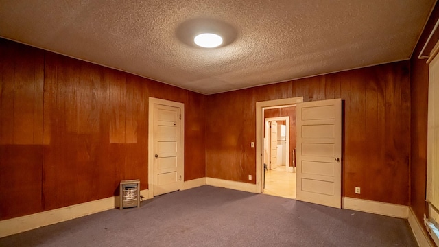 224 Pecan St, Dublin, TX 76446 - carpeted empty room with wood walls, a textured ceiling, and baseboards