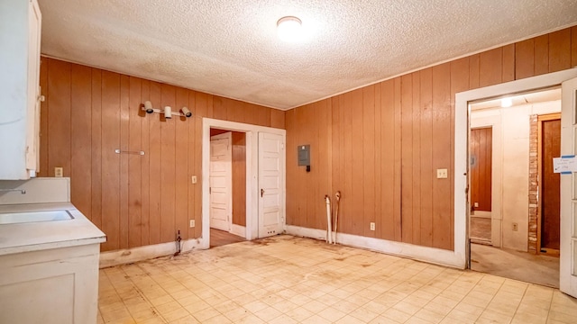 224 Pecan St, Dublin, TX 76446 - unfurnished room featuring a sink, wooden walls, a textured ceiling, light flooring, and baseboards