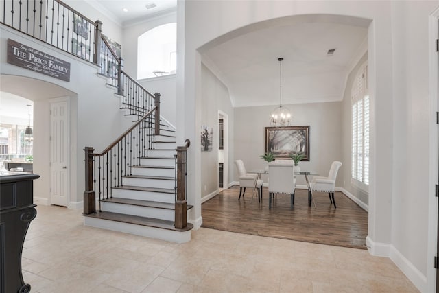 8008 Craftsbury Ln, Mckinney, TX 75071 - foyer entrance featuring crown molding, a chandelier, arched walkways, stairway, and light tile patterned floors
