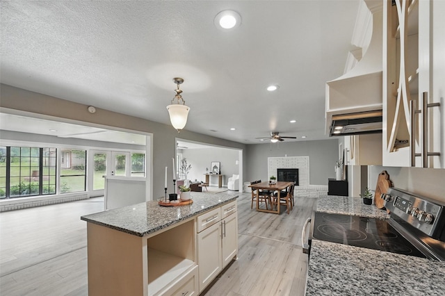 1700 N Preston St, Ennis, TX 75119 - kitchen featuring stainless steel range with electric cooktop, open shelves, open floor plan, a fireplace, and light wood-style floors