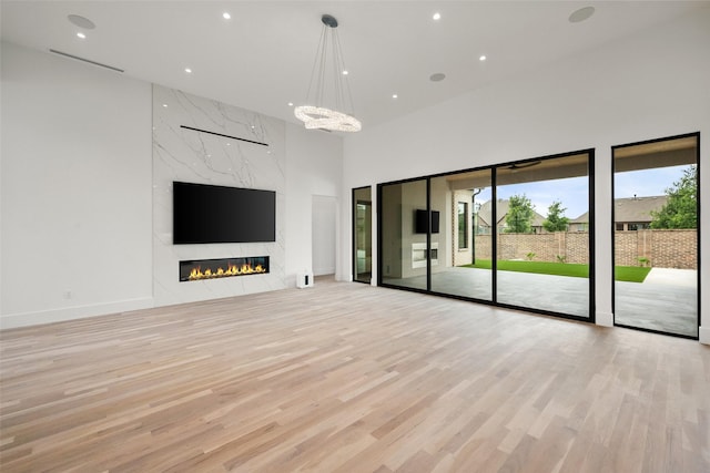 1106 Knoll Crest Dr, Mansfield, TX 76063 - unfurnished living room featuring light wood-type flooring, a high ceiling, recessed lighting, a premium fireplace, and a chandelier