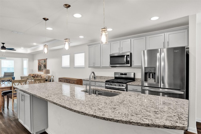 7668 Monument Dr, Little Elm, TX 76227 - kitchen featuring appliances with stainless steel finishes, ceiling fan, dark wood-style flooring, a center island with sink, and light stone counters