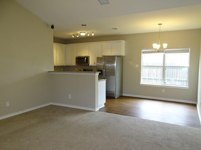 2013 Alanbrooke Dr, Fort Worth, TX 76140 - kitchen with stainless steel appliances, carpet flooring, a chandelier, white cabinets, and a peninsula