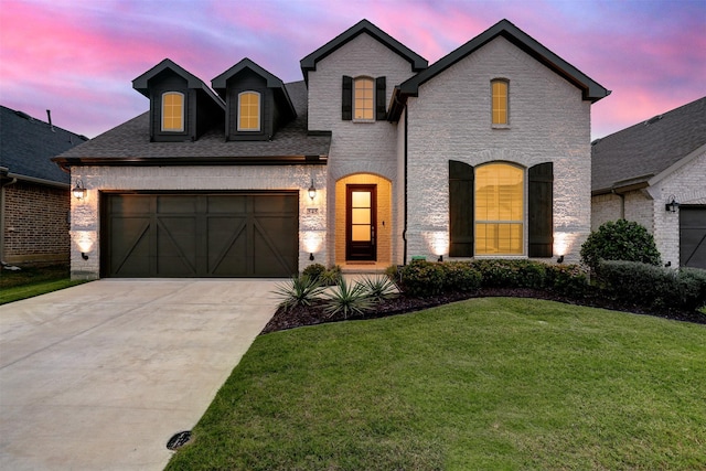 545 Oakmoss St, Little Elm, TX 76227 - french country inspired facade featuring concrete driveway, brick siding, an attached garage, and a lawn